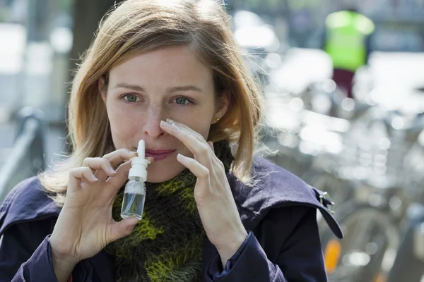 Kobieta za pomocą sprayu do nosa — Zdjęcie stockowe