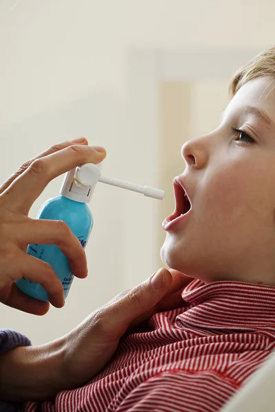 Kind met behulp van spray in mond — Stockfoto