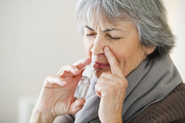 Äldre person som använder nässpray — Stockfoto