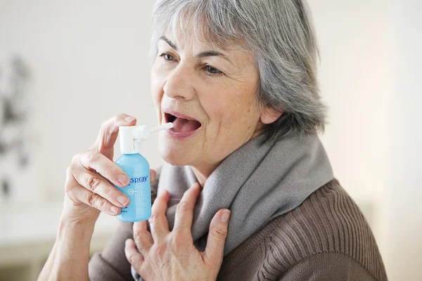 Persona de edad avanzada usando spray bucal —  Fotos de Stock