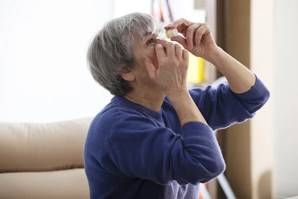 Bejaarde gebruik van oog lotion — Stockfoto