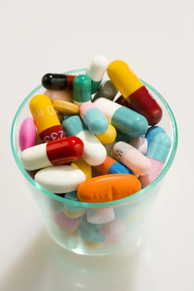 Tabletler ve kapsüller bir cam — Stok fotoğraf