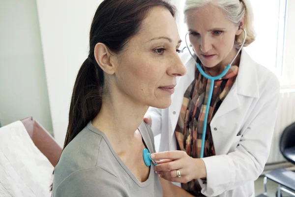 Läkaren lyssnar på patienten med ett stetoskop — Stockfoto