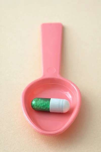 Capsule in a spoon — Stock Photo, Image