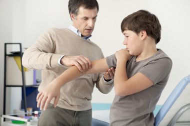 Doctor examines the boy's hand clipart