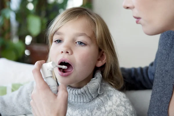 Kind met behulp van spray in mond — Stockfoto