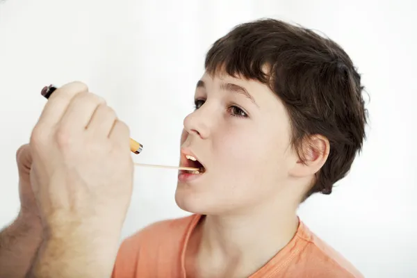 Doctor examines the throat of a boy — Stock Photo, Image