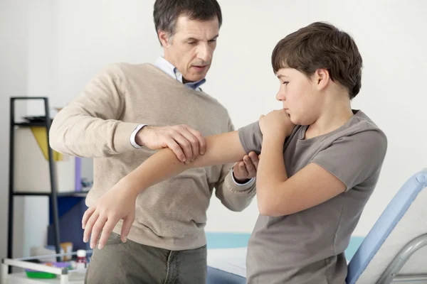 Arzt untersucht die Hand des Jungen — Stockfoto