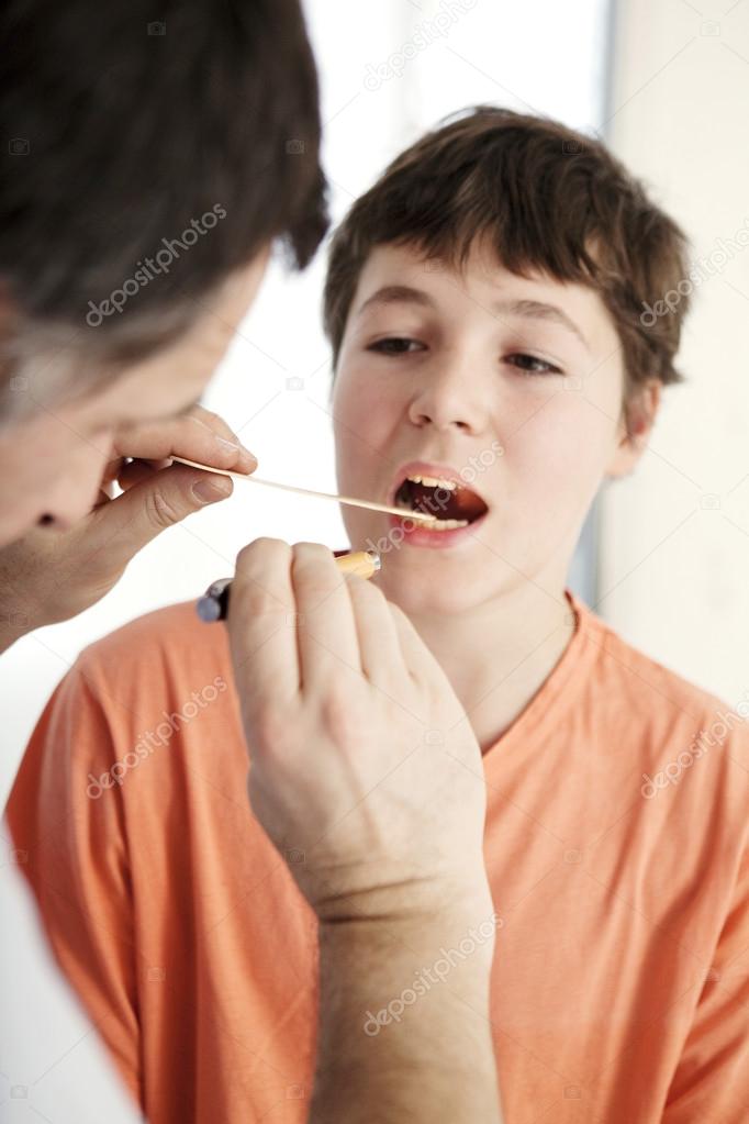 Doctor examines the throat of a boy