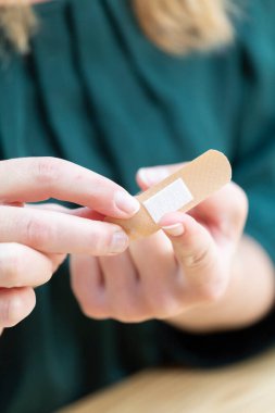 Young woman putting a bandage on her finger.
