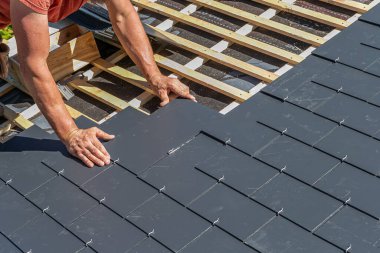 Close-up of the gesture of the hands of the roofer for the installation of the slates.