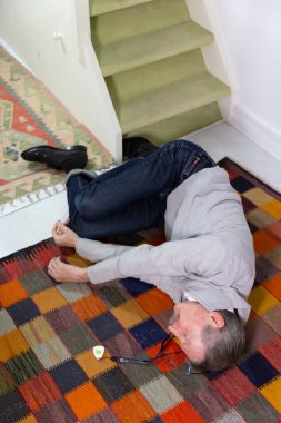 Elderly man with a medical alert system who has fainted and fallen down stairs.