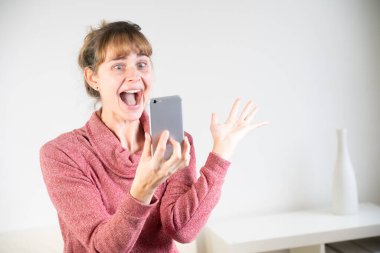 Extremely joyful woman at the sight of her new smartphone.