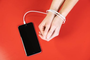 Woman's hands tied by the cord for charging a smartphone.