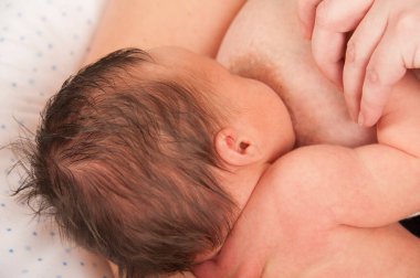 Mother breast feeding 2-week-old baby.