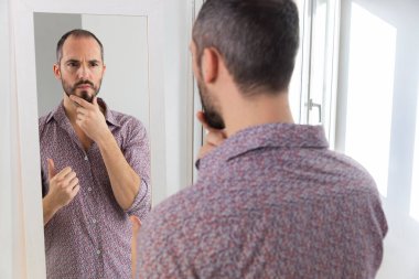 A man looking in a mirror to give him self-confidence.