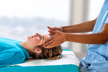 Genç bir kadını manipüle eden fizyoterapiste yakın plan. El masajıyla spa yatağında yatan bir kız.