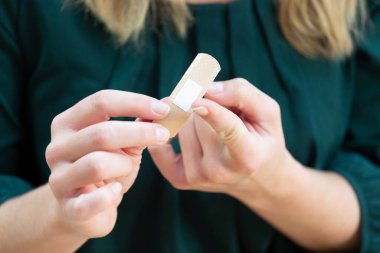 Young woman putting a bandage on her finger.