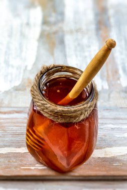 Single jar of honey containing a wooden stick.