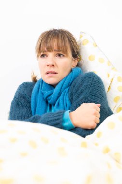 A young woman in bed suffering from a flu-like condition.