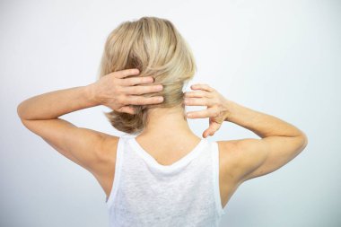 A woman feeling pain in her neck.