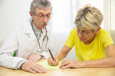 Physician doing writing rehabilitation for a woman with Parkinson's disease.