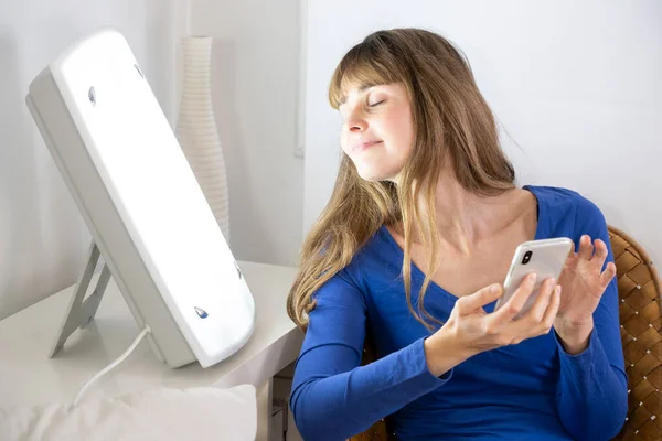 Woman Sitting Her Smartphone Light Therapy Lamp — ストック写真