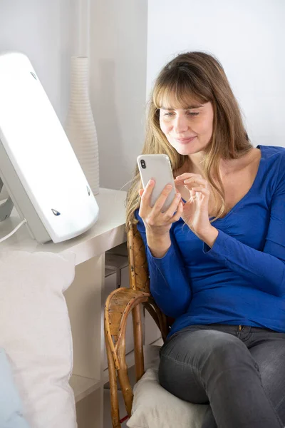 Woman Sitting Her Smartphone Light Therapy Lamp — Stockfoto