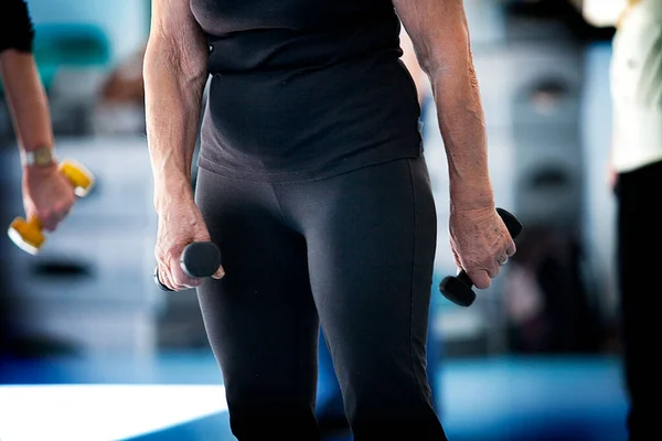 Senior Woman Taking Gymnastics Class Wearing Dumbbells — Fotografia de Stock