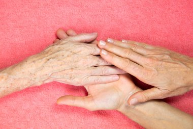 An elderly woman and young womans hands. 