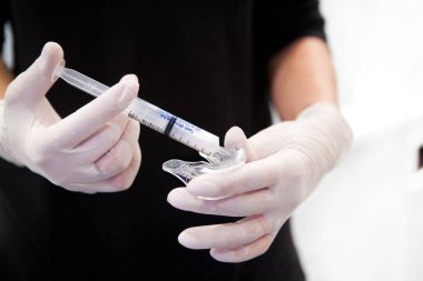 Teeth whitening by applying a gel in a tray and exposure to an LED lamp.