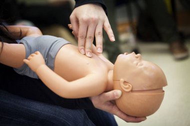 First aid training on a mannequin: cardiac massage on an infant.