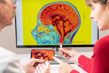 Researcher explaining to a woman how a smartphone can be connected to a brain.