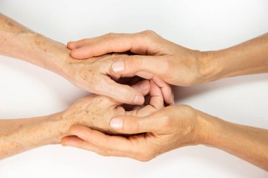 An elderly woman and young womans hands. 