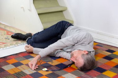 Elderly man with a medical alert system who has fainted and fallen down stairs.