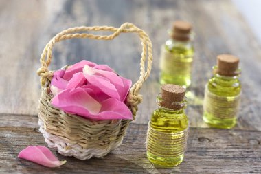 Rustik hasır sepet pembe kuşburnu çiçek ve şişeler gerekli Gül yağı ile.