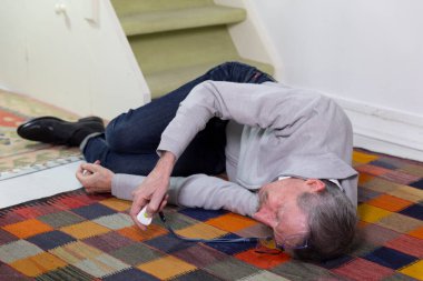 Elderly man with a medical alert system who has fainted and fallen down stairs.