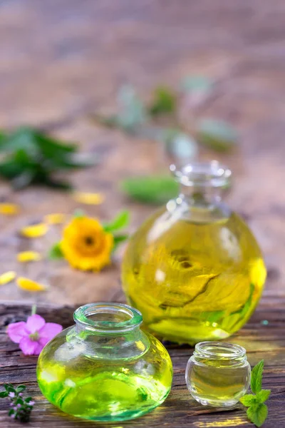 Alternative medicine with essential oils, bottle potion and flowers on a wooden table.