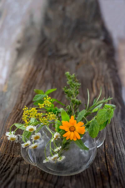 Tea-potof herbal tea plant and, flowers isolated on wooden background