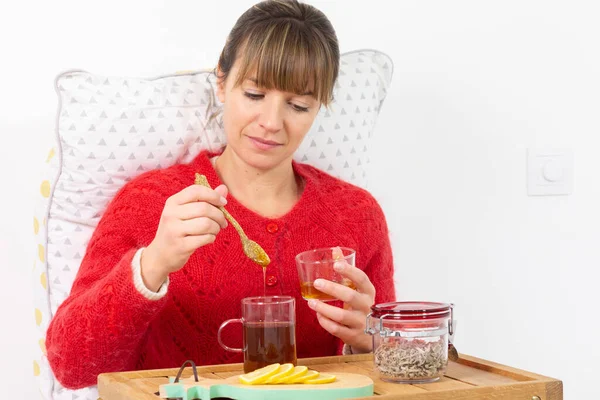 Young woman in bed with a slice of lemon, herbal tea and honey.