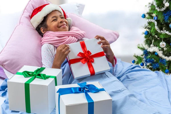 小女孩头戴圣诞礼帽 住院期间接受着她的礼物 — 图库照片