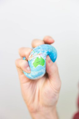 A man gripping a stress ball in the shape of the earth.