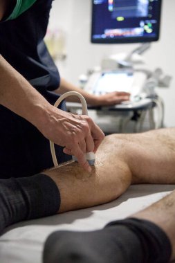 In a radiology center, a radiologist performs a Doppler ultrasound on a patient with varicose veins.