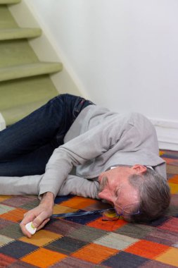 Elderly man with a medical alert system who has fainted and fallen down stairs.