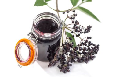Jar of homemade elderberry confiture and fresh fruits