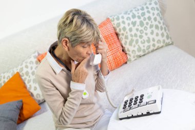 Elderly woman using a telephone with large buttons for elderly people.