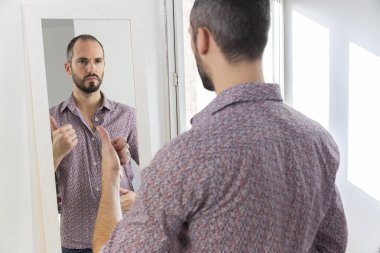A man looking in a mirror to give him self-confidence.