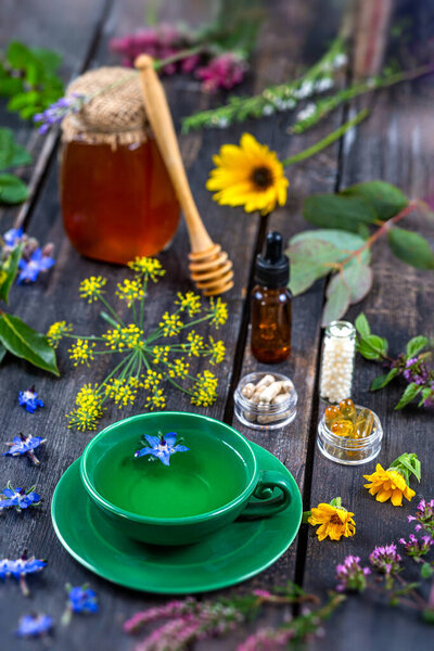 Herbal tea, food supplements, homeopathy, honey, essential oil surrounded by medicinal plants and flowers.