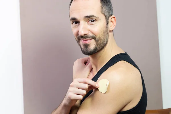 A man putting a nicotine patch on.