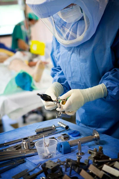 Orthopedic surgery, a nurse prepares the surgical instruments for the fitting of a knee prosthesis.